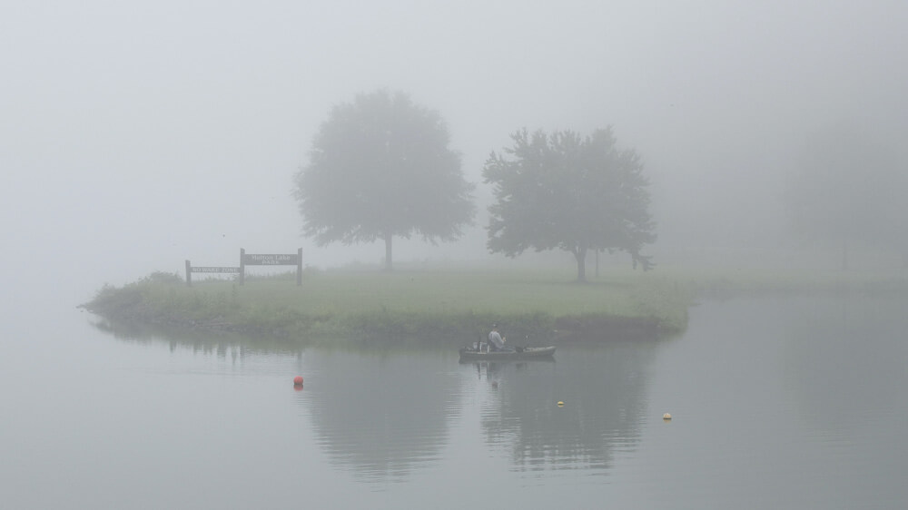 霧の中の池に浮かぶ小舟