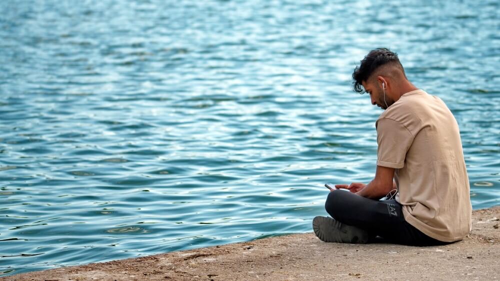 海辺でスマホを使う男性